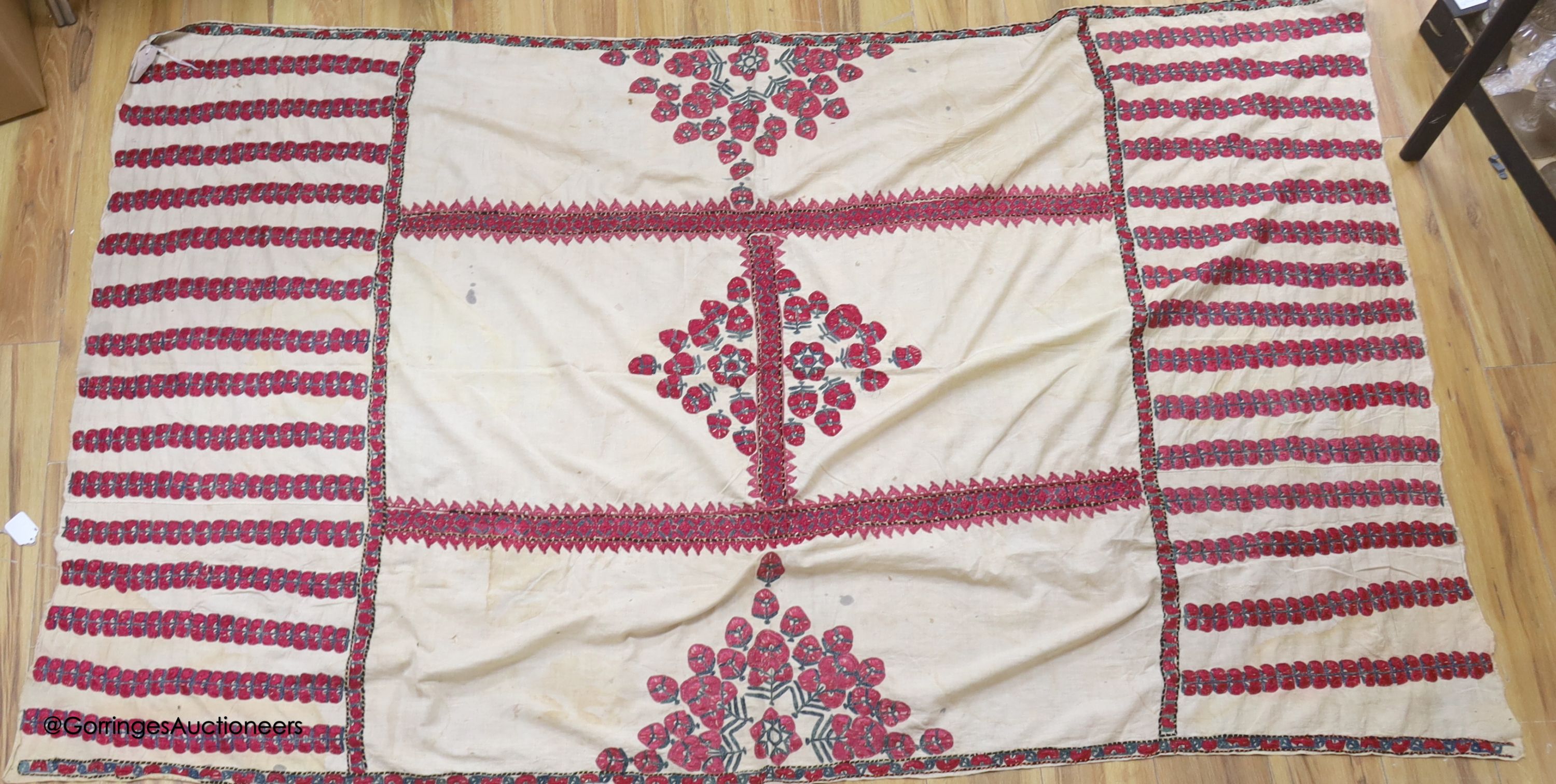 A silk embroidered Suzani, embroidered with cherry red flower heads with green stems and leaves in fine silk, width 134cm length 220cm